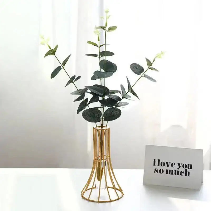 Gold vase metal flowers with dark green eucalyptus branches and white flowers for modern desk decoration