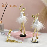 Golden and white ballet girl resin figurines with feathered tutus and delicate detailing on black circular bases for decor