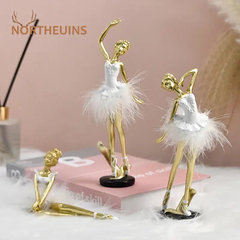 Golden and white ballet girl resin figurines with feathered tutus and delicate detailing on black circular bases for decor