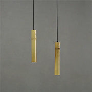 Two slender golden bamboo tube pendant lights with adjustable wire hang against a neutral gray backdrop for dining rooms