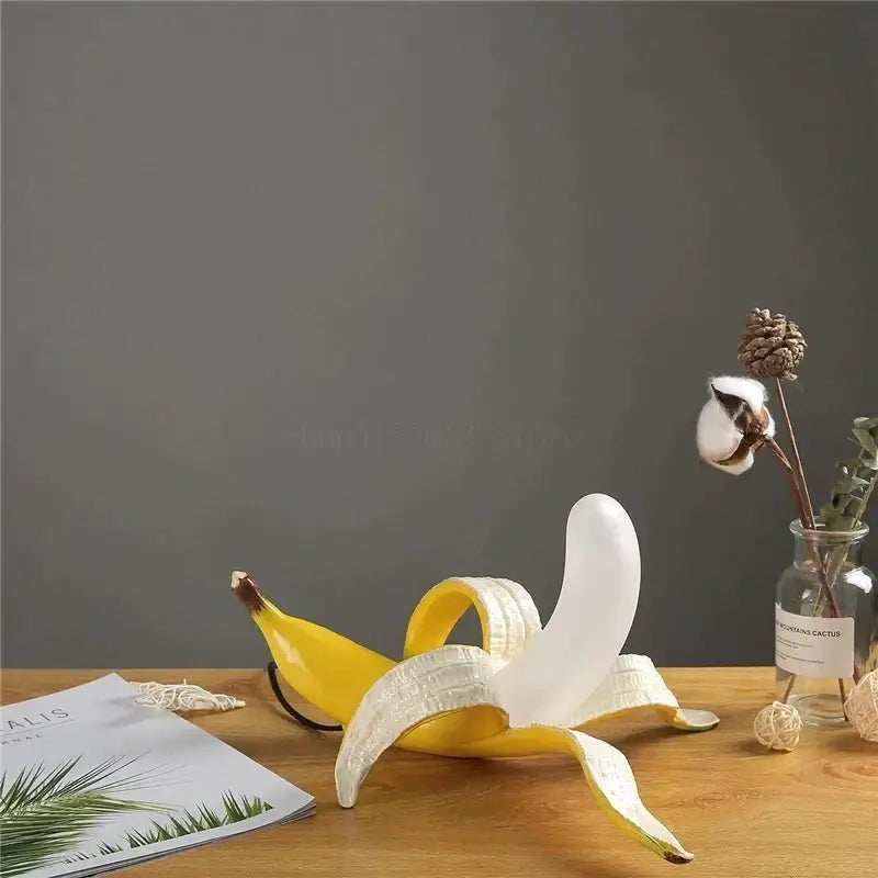 A glossy yellow and white ceramic banana sculpture with peeled peel designed as decorbites glass lampshade night light