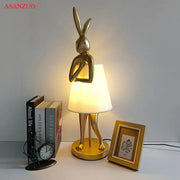 Golden bathing rabbit resin table lamp with sleek metallic finish and soft white fabric shade for bedroom decorbites decor