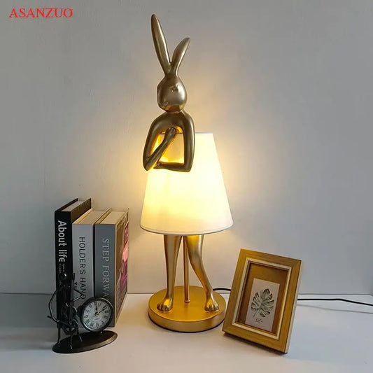 Golden bathing rabbit resin table lamp with sleek metallic finish and soft white fabric shade for bedroom decorbites decor