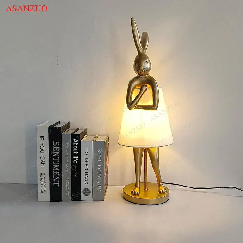 Golden bathing rabbit resin table lamp with sleek metallic finish and soft white fabric shade for bedroom decorbites decor