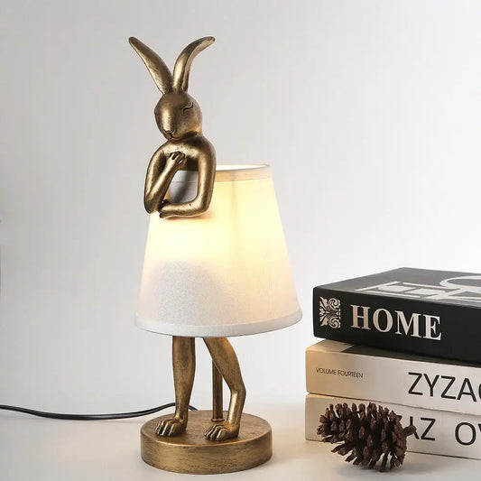 Golden bathing rabbit resin table lamp with metallic finish and textured white fabric shade for bedroom decorbites decor