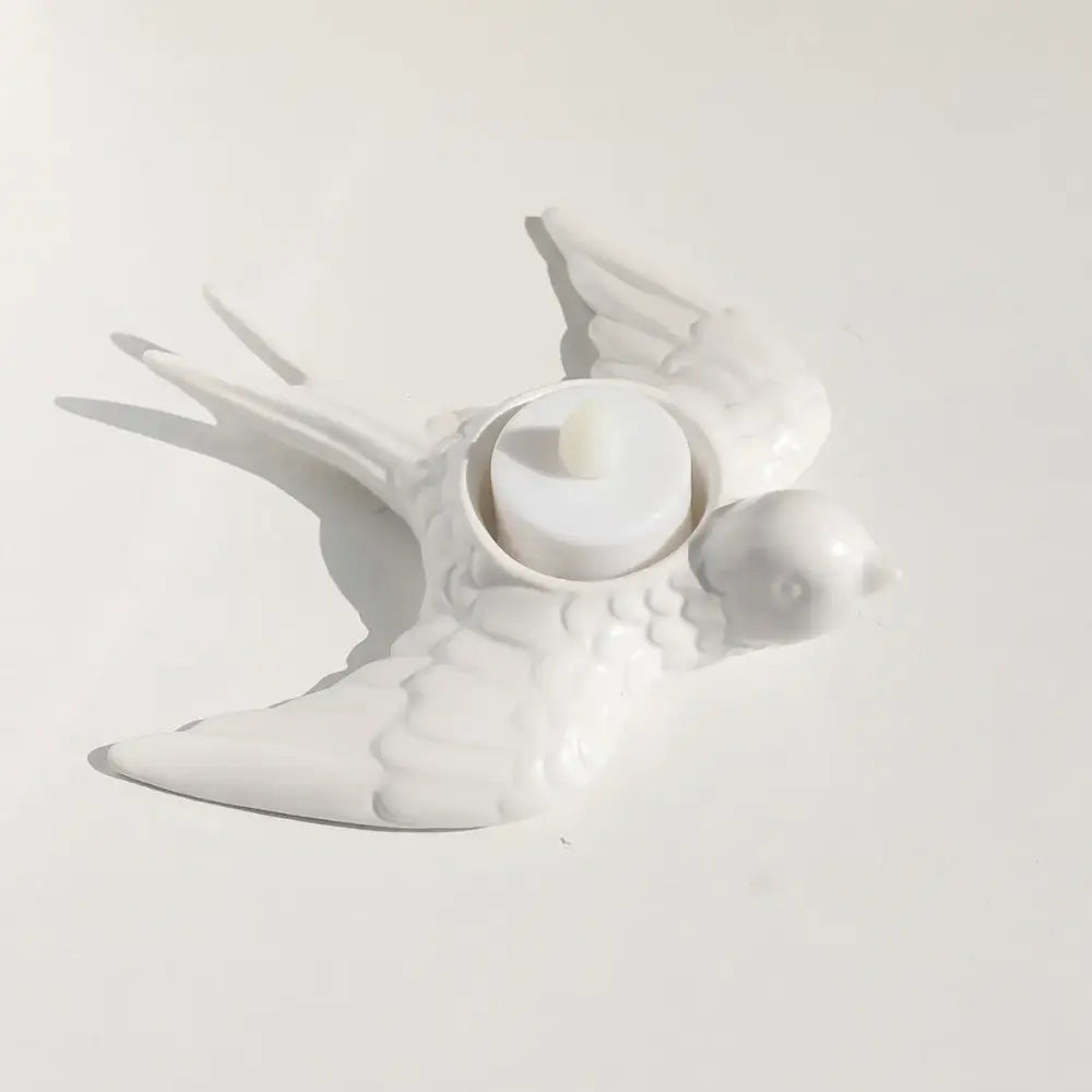 White ceramic bird-shaped candle holder tray with circular indentation holding white tea light for wedding decor