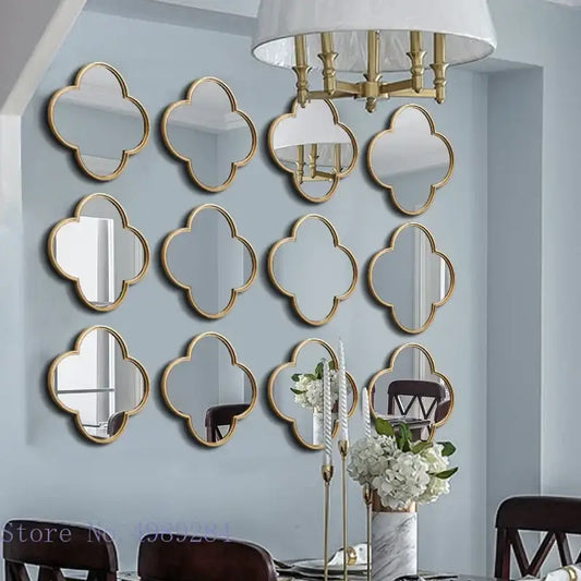 Set of twelve gold-framed geometric plum flower quatrefoil mirrors with golden border on light blue living room wall decor