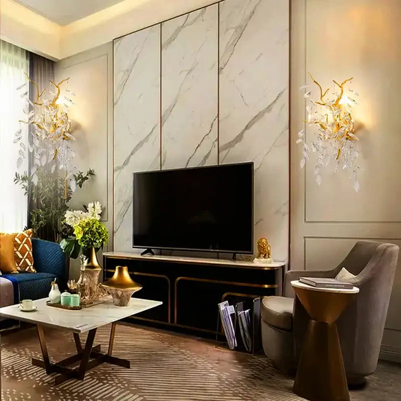 Black flat-screen television mounted on marble wall near golden branch decorbites crystal wall lamp leaf sconce
