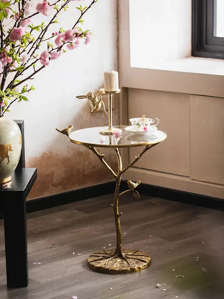 Golden brass bird tree side table with reflective glass top and intricate branch-like base for living room decorbites brass bird decor