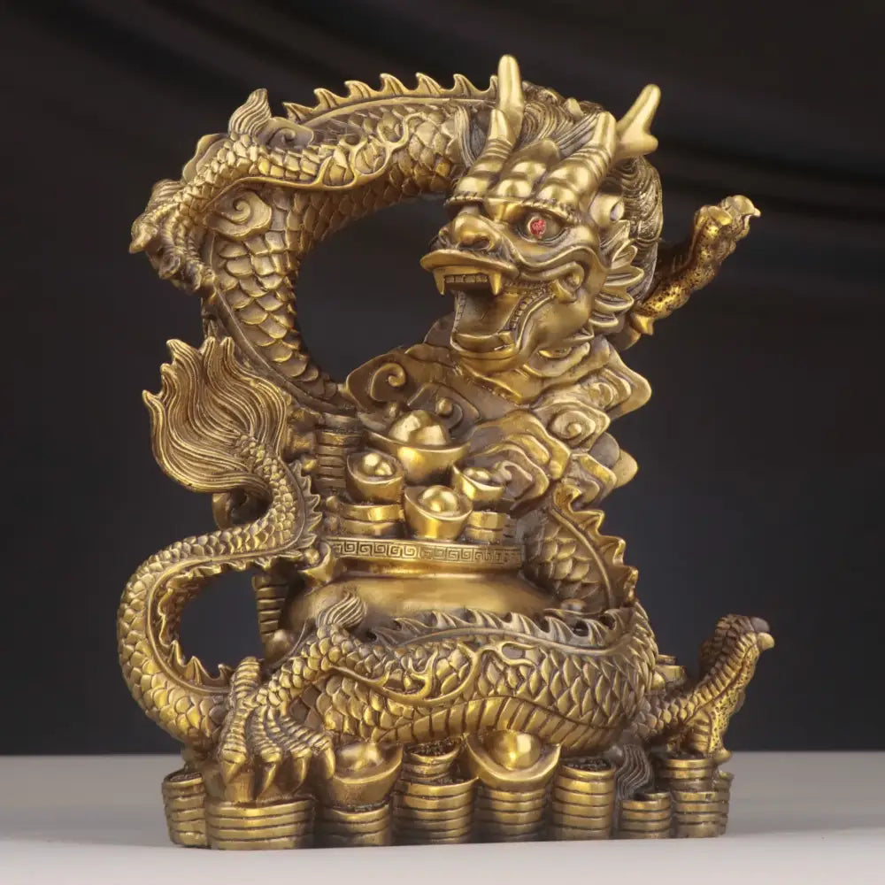 Golden brass dragon copper bowl ornament with intricate scales and red eye seated atop stacked coins for decor