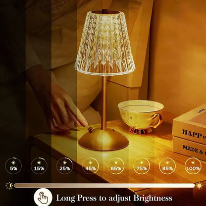 A warm-toned brass-finished table lamp with faceted crystal diamond touch sensor shade for bedroom use