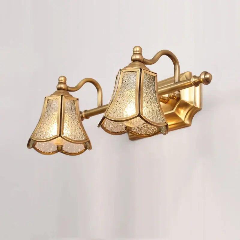 Gold-toned brass wall sconce with two bell-shaped textured glass shades for decorbites golden glass mirror vanity fixture