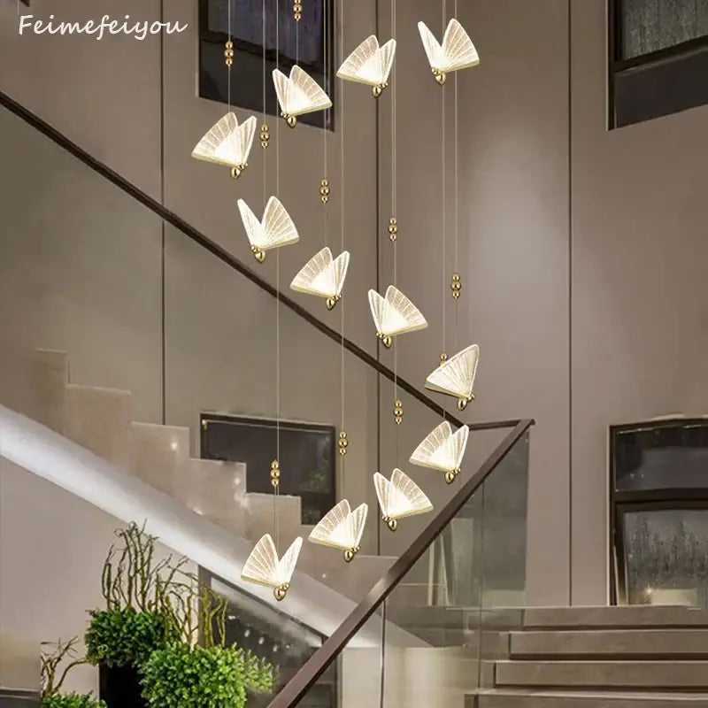 Golden iridescent butterfly pendant light with translucent white wings and gold accents suspended above staircase decorbites butterfly pendant