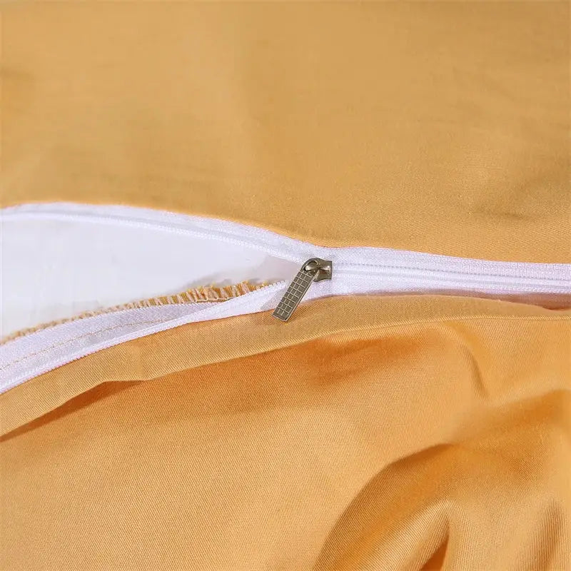 A metallic zipper with a grid-patterned pull tab on an orange decorbites golden jacquard cotton bedding set seam