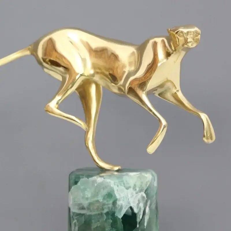 Golden leopard brass figurine with sleek metallic surface on textured green marble base for living room decorbites decor