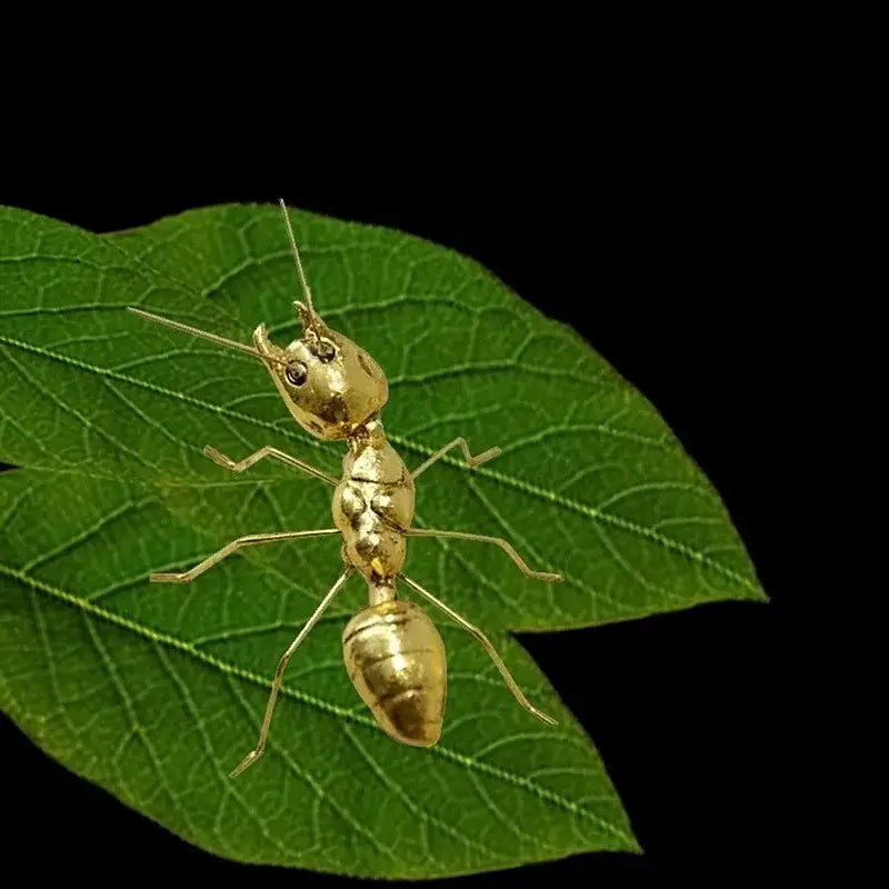 Golden metal ants decorative figurines with detailed segmented bodies resting on a green leaf for home decor
