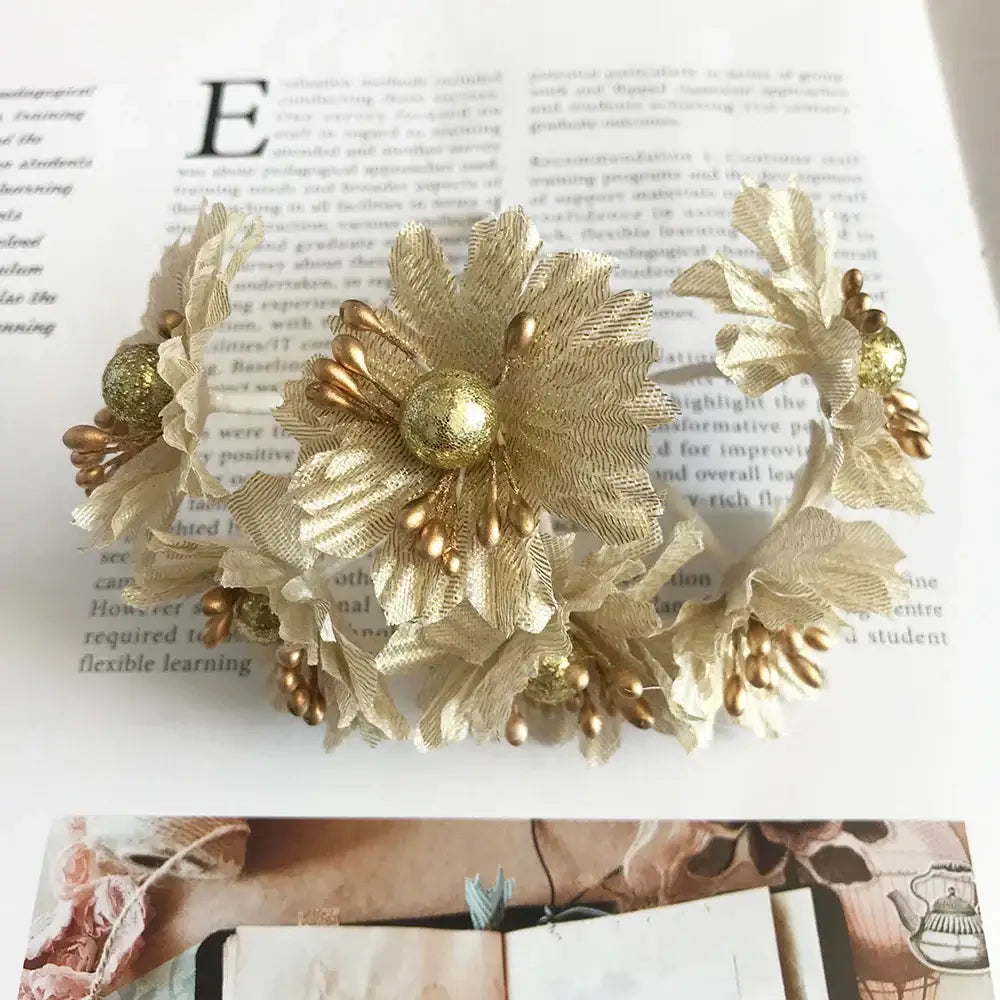 Elegant gold-toned floral headband with textured fabric petals and metallic beads for decorbites green plant berry stamen decor