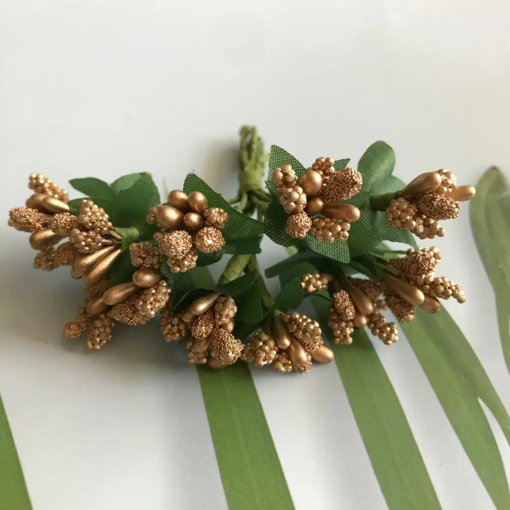 A cluster of golden metallic berry stamen flowers with glittery petals and green fabric leaves for decorbites green plant decor