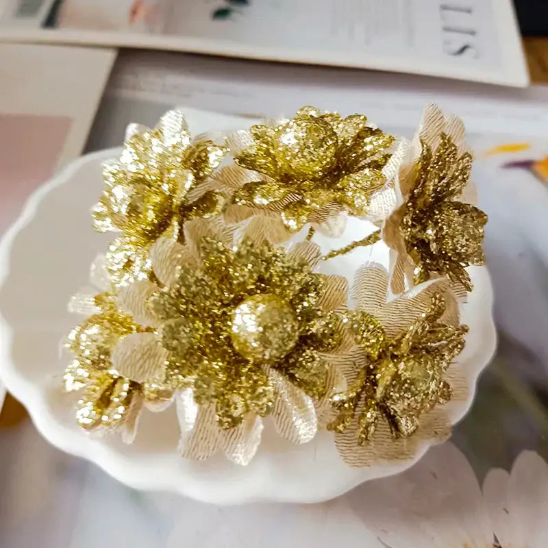A cluster of glittery gold fabric flowers with berry stamen and green plant foliage for decorbites green plant decor