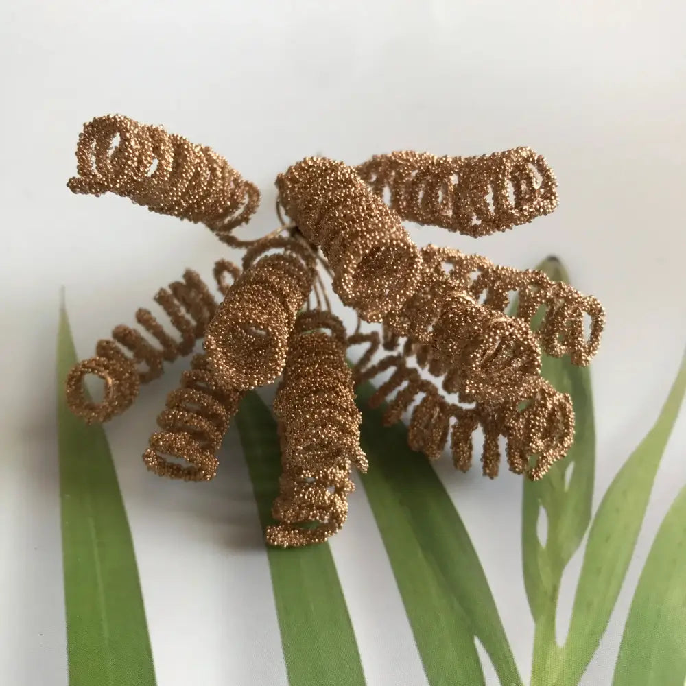 Golden metallic berry stamen decor with green plant foliage featuring glittery spiral wire and beaded texture by decorbites