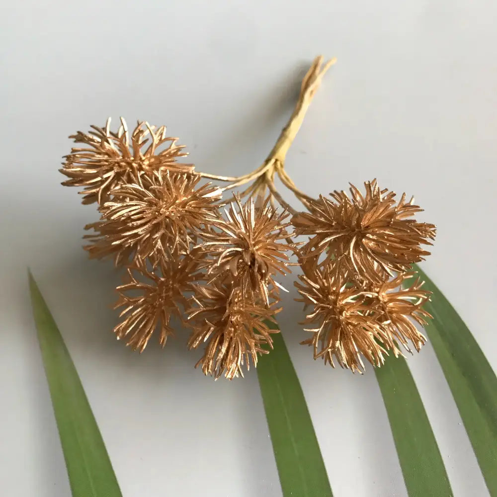 Golden metallic spiky flower cluster brooch with intricate design featuring berry stamen and green plant decorbites accents