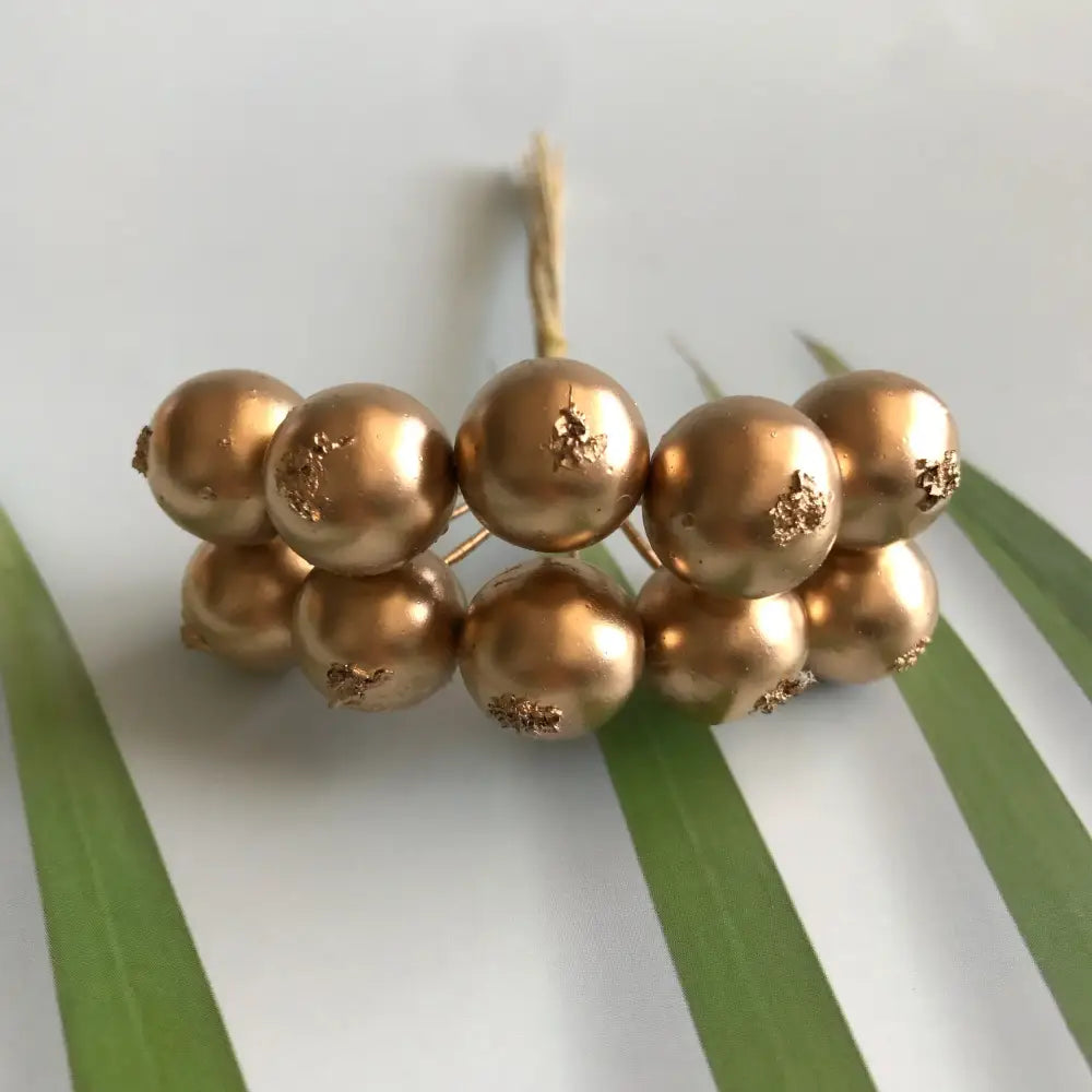 A cluster of golden metallic berry stamen with gold leaf accents and green plant foliage for decorbites green plant decor