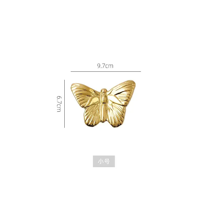 Gold-colored metallic butterfly pin with detailed wing textures as part of a golden wall decoration set for living room