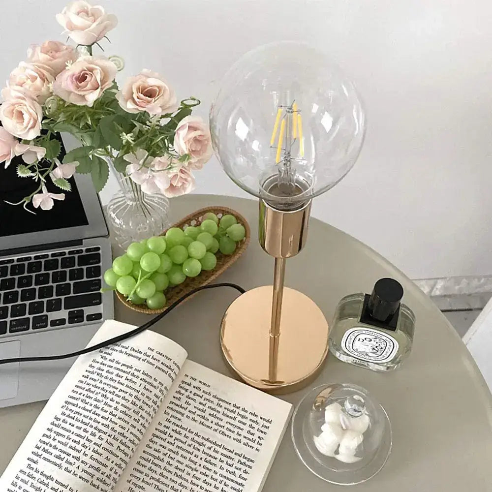 A sleek decorbites golden modern led desk lamp with a brass base and clear glass globe shade for bedroom decor