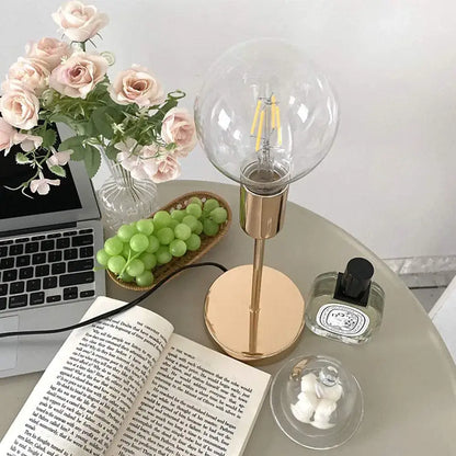 A sleek decorbites golden modern led desk lamp with a brass base and clear glass globe shade for bedroom decor