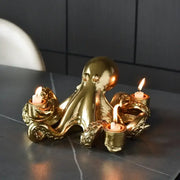 Golden octopus sculpture candle holder with three lit candles in ornate textured cups for dining room decorbites decor