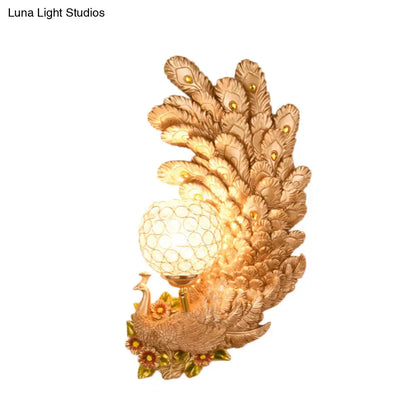 Golden peacock wall light with crystal shade featuring intricate feather details and a yellow green textured glowing globe bulb