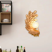 Golden peacock wall light with crystal shade featuring intricate feathers and yellow green textured glowing globe bulb
