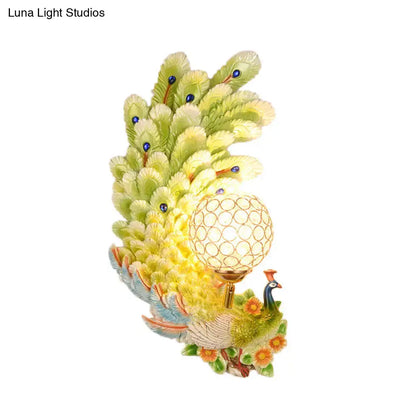 Golden peacock wall light with crystal shade featuring yellow green feathers and orange floral accents for living room use