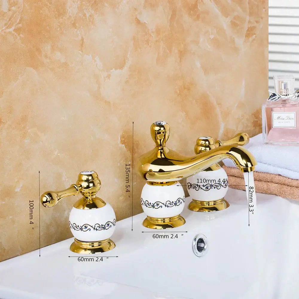 Golden plated bathroom faucet set with gold-finished ceramic and ornate black scrollwork on white porcelain handles by decorbites