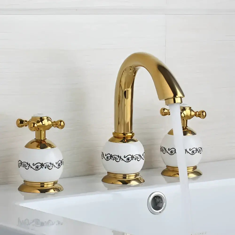 Golden plated bathroom faucet set with three handles and white ceramic knobs featuring black scrollwork decorbites golden plated