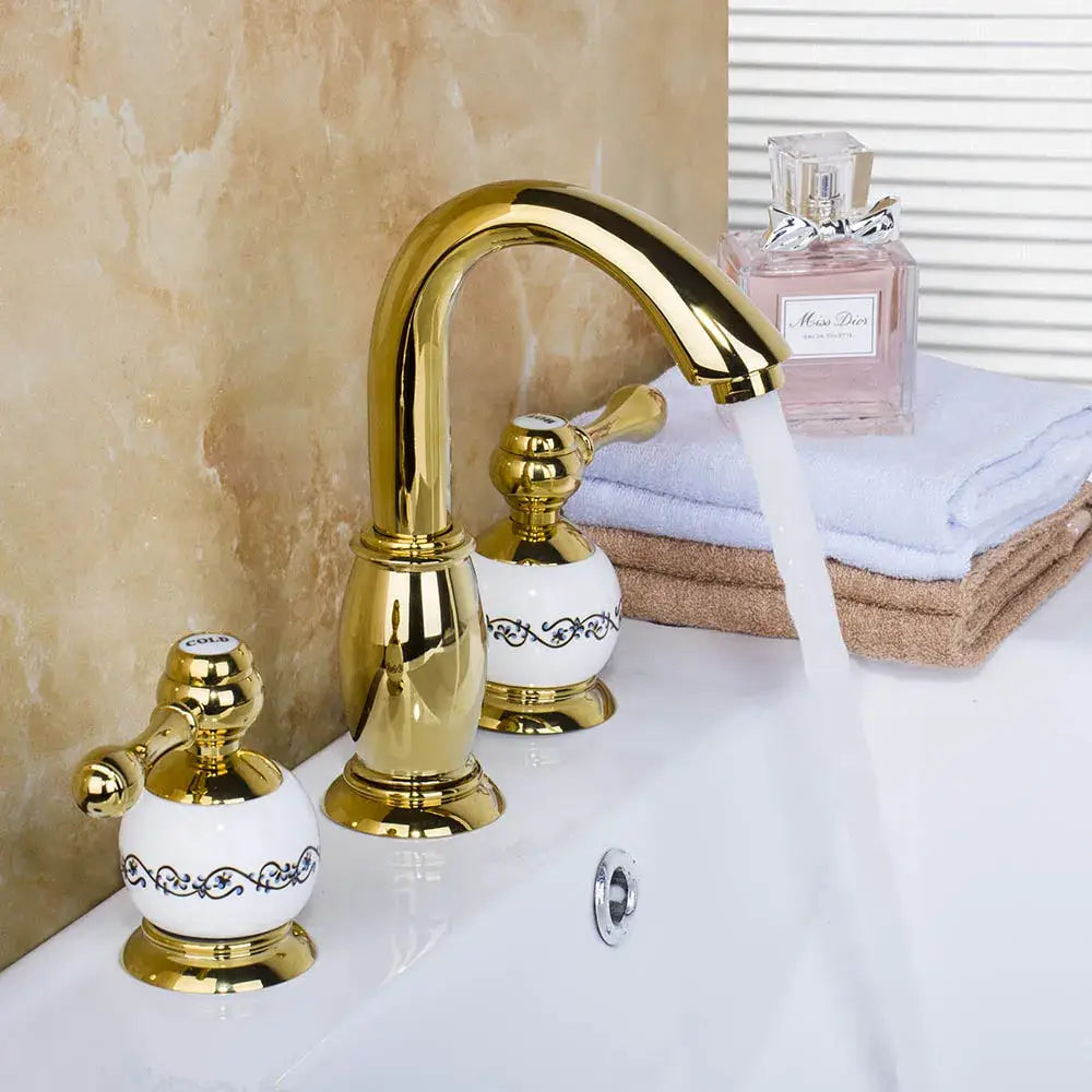 Golden plated bathroom faucet set with white ceramic handles featuring black floral patterns by decorbites