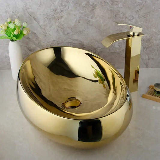 Golden plated ceramic basin sink with oval shape and sleek reflective metallic finish for bathroom decorbites golden plated