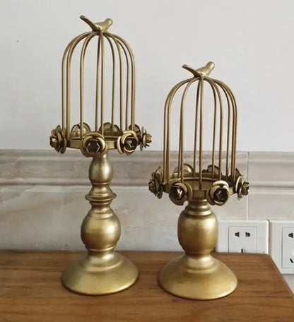 Golden metal birdcage style ornament candle holders with ornate floral detailing and small bird accents for dining rooms