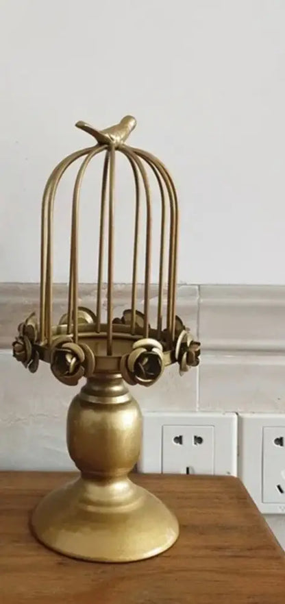 Golden metal birdcage style ornament with rose accents and a small bird, designed as a dining room candle holder