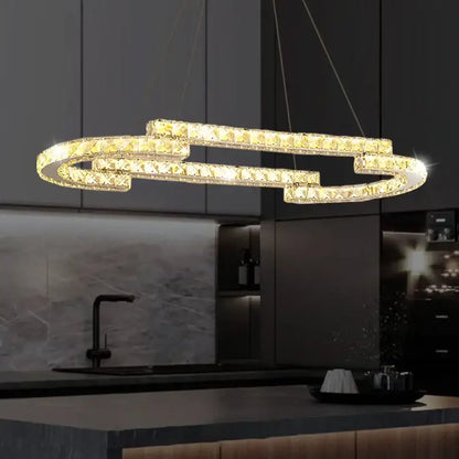 A modern gold-toned decorbites circular crystal pendant light with interlocking ring design above kitchen counter