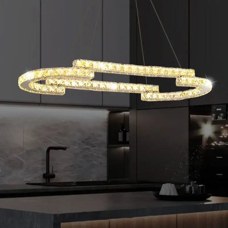 A modern gold-toned decorbites circular crystal pendant light with interlocking ring design above kitchen counter
