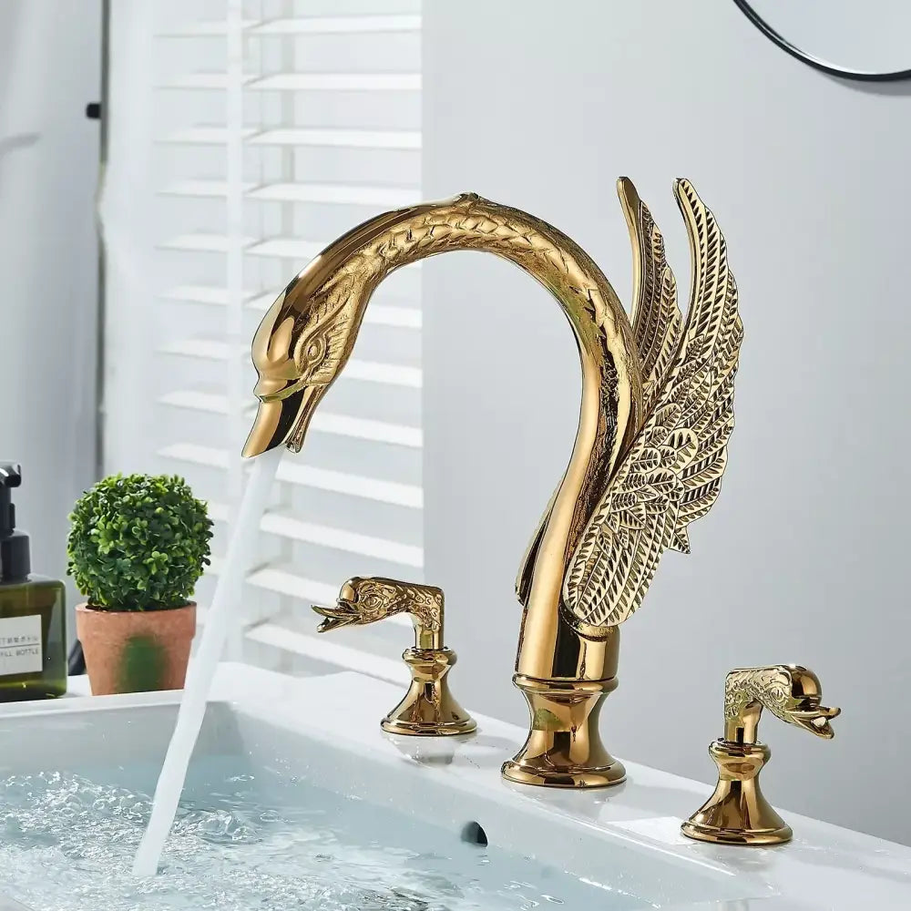 Golden swan dual handle deck mounted bathroom basin tap with intricate feather detail and matching dolphin cold water handles