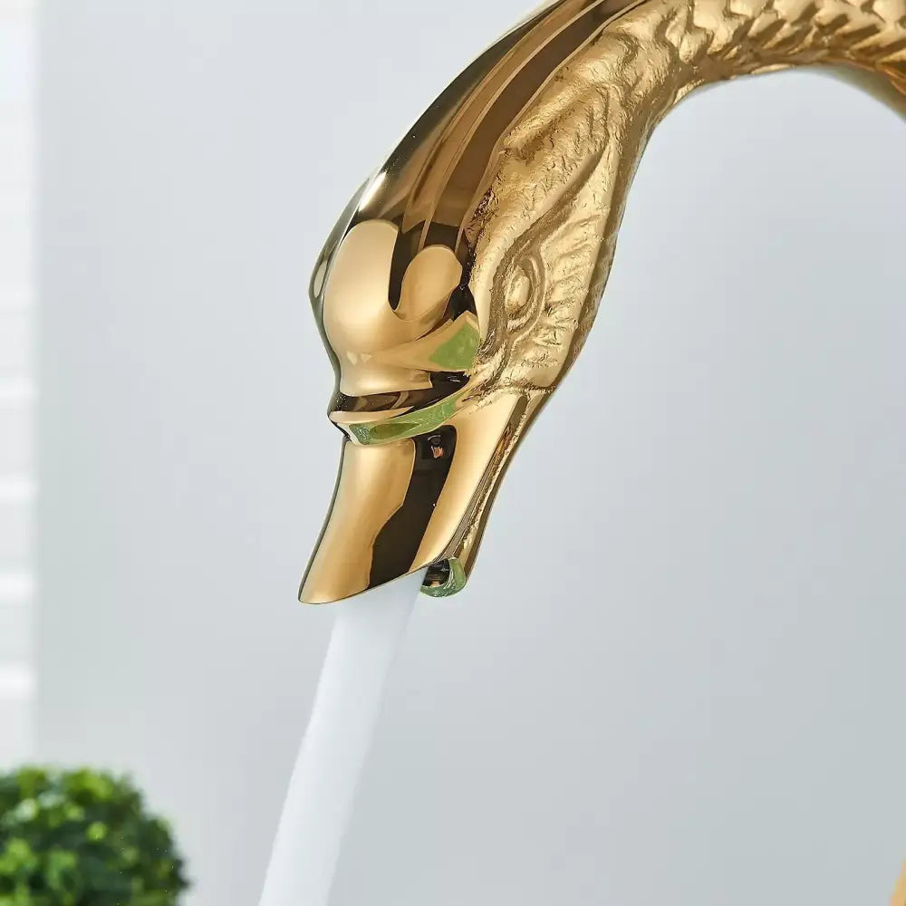 Golden swan dual handle deck mounted bathroom basin tap with polished metallic finish and detailed feathered neck for cold water
