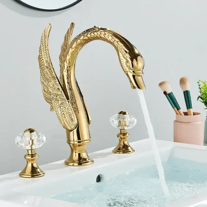 Golden swan dual handle deck mounted bathroom basin tap with intricate feather detailing and crystal knobs for cold water