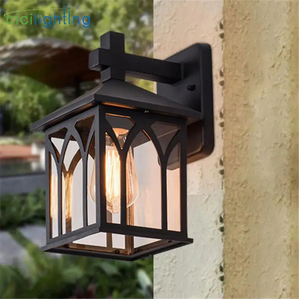 Gothic arched black wrought iron led wall lamp with clear glass panels and visible filament bulb for outdoor use