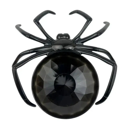 Black spider-shaped brooch with faceted black crystal body and glossy metal legs on gothic gemstone skull spider tray storage plate