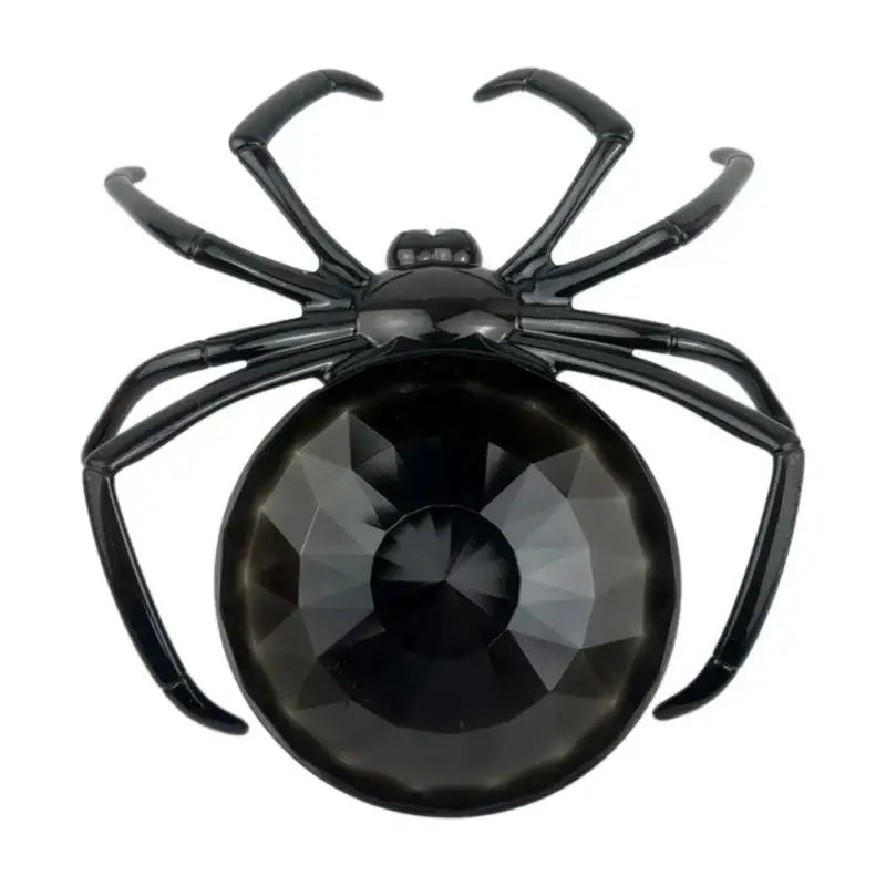 Black spider-shaped brooch with faceted black crystal body and glossy metal legs on gothic gemstone skull spider tray storage plate