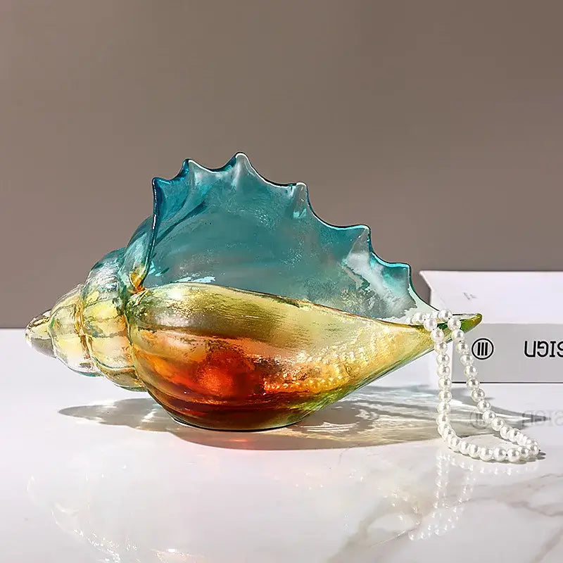 A translucent glass seashell key tray with gradient teal amber and gold hues from decorbites conch glass handicrafts