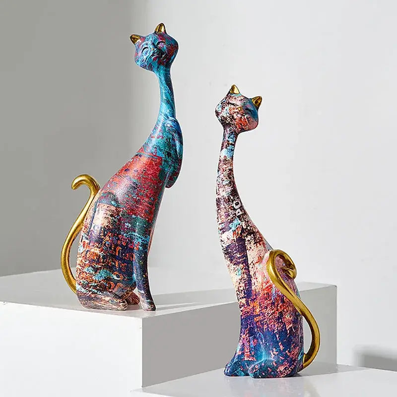 Two abstractly painted cat lovers resin figurines with gold-tipped ears and vibrant blue red purple decorbites accents