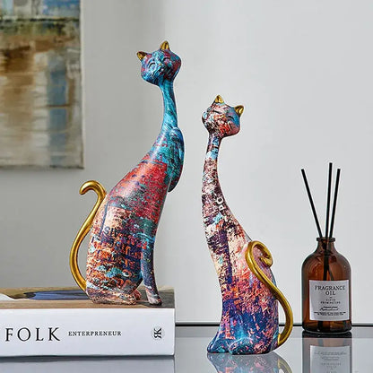 Two stylized cat lovers resin figurines with vibrant blue red purple paint splatter and gold accents for decorbites cat lovers